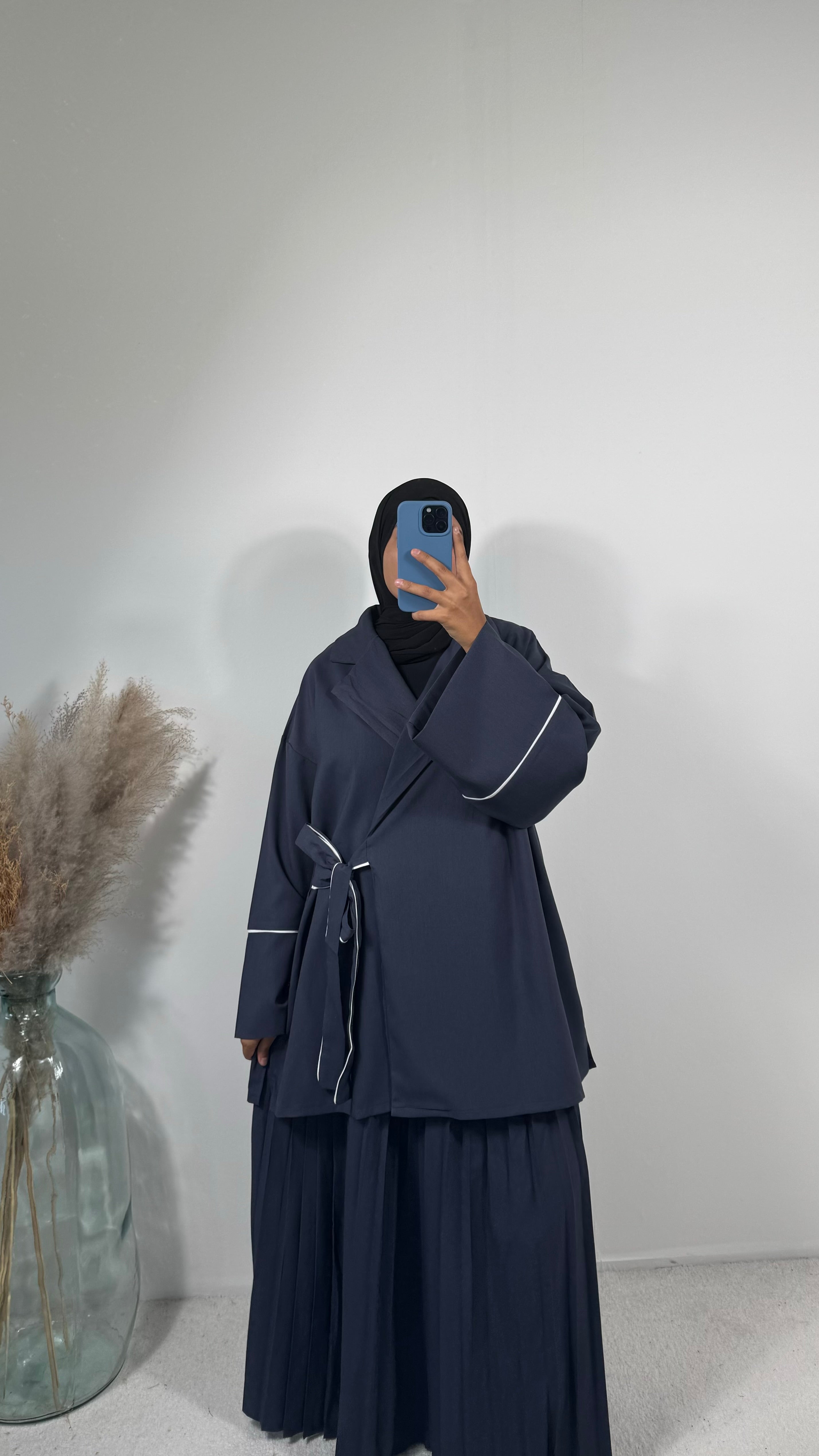 Jupe plissée bleu marine associée à une veste légère, idéale pour la mi-saison.