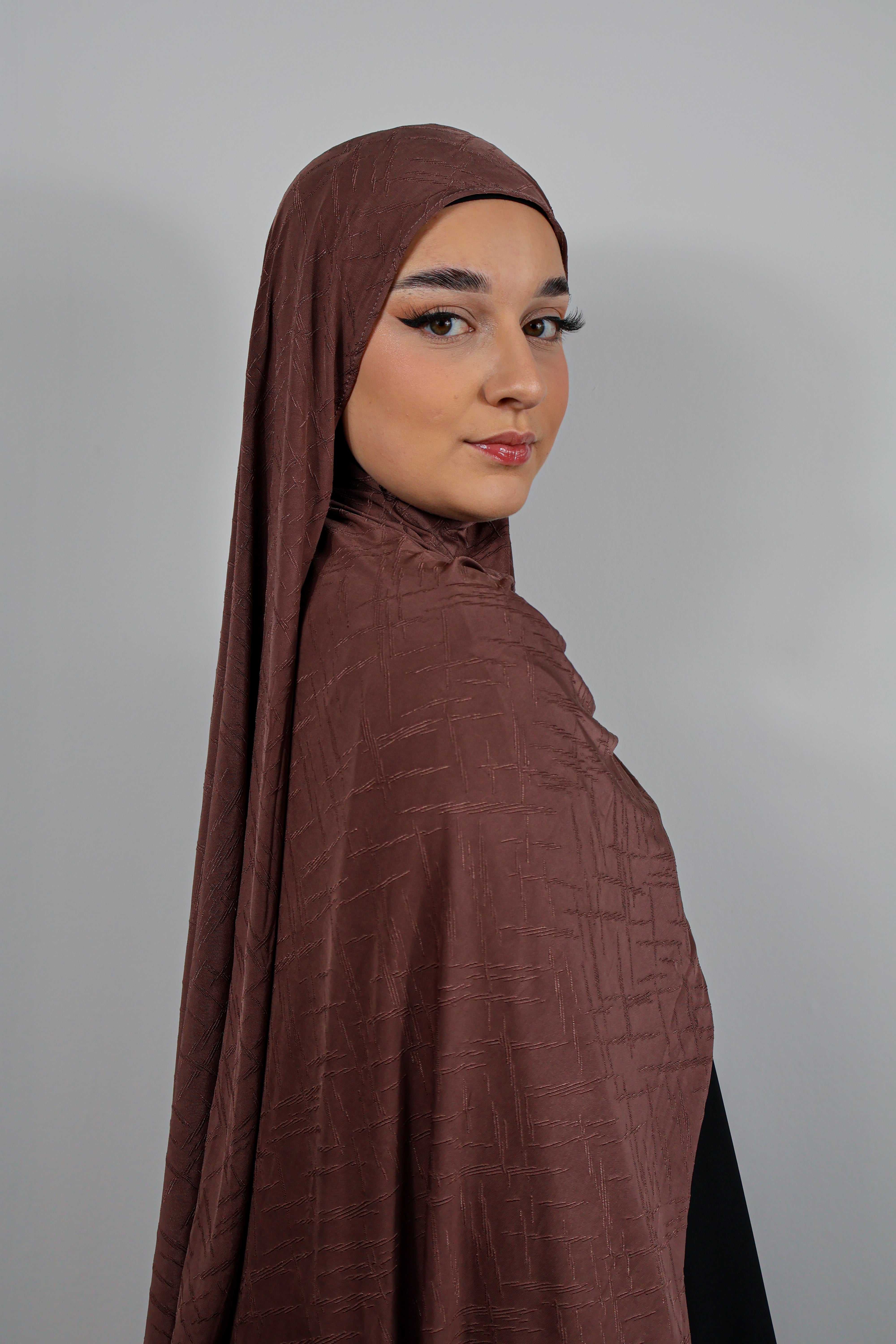 Femme portant un hijab en Jersey Prestige kaki, associé à une abaya noire fluide.