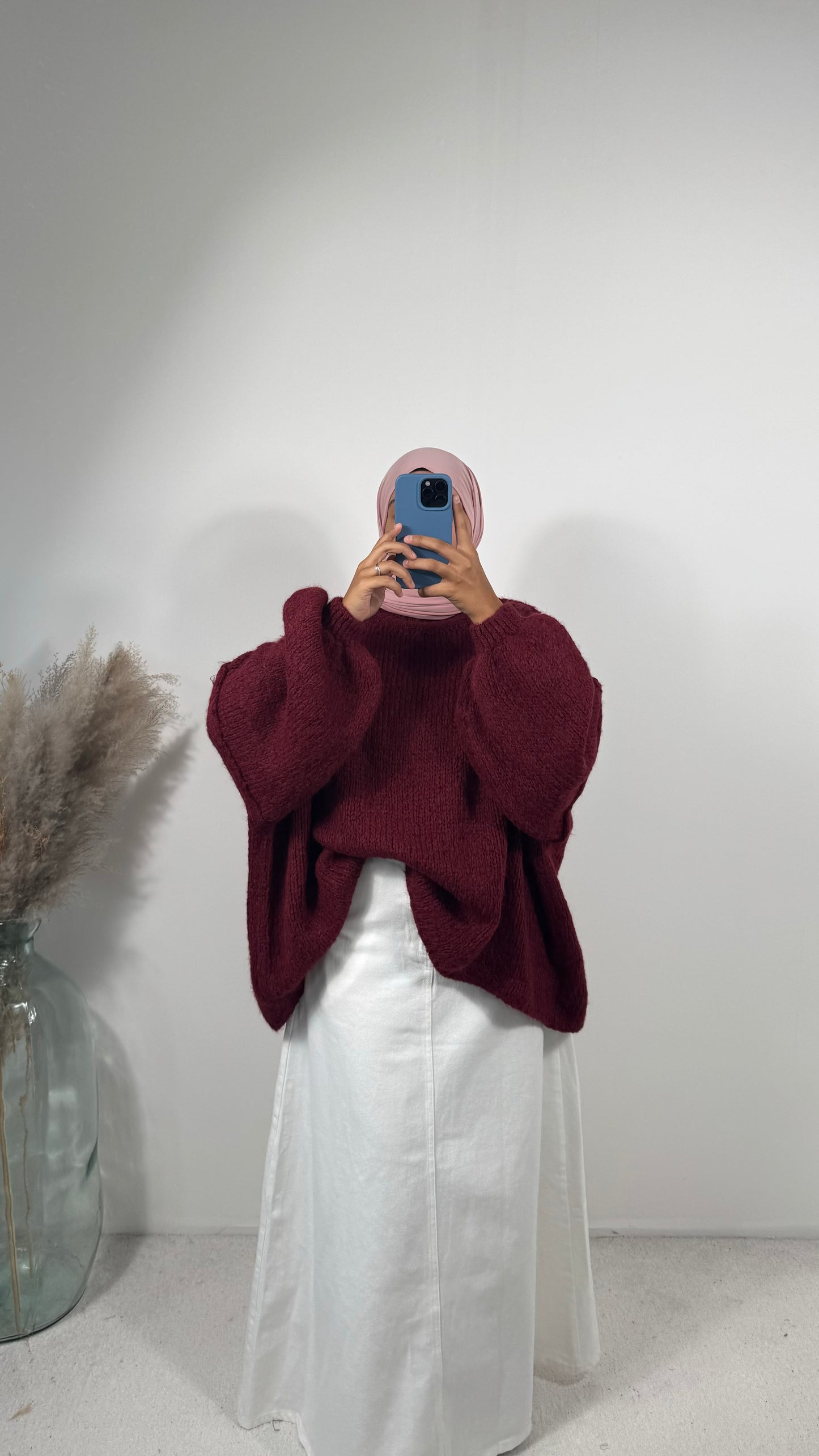 Femme portant un pull en laine oversize rose pastel avec une jupe longue.