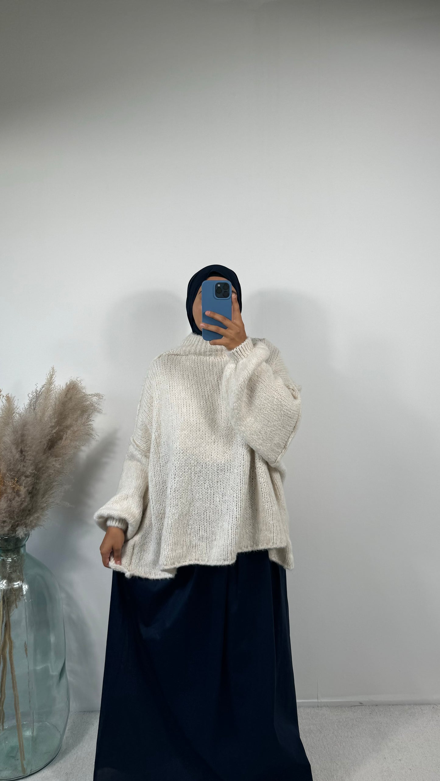 Tenue décontractée avec pull en laine beige oversize et jupe fluide noire.